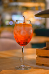 A glass with the red citrus cocktail. Alcohol summer beverage in a wine glass. Refreshing drink with ice.