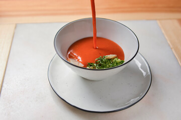 Tomato soup with shrimps and salmon in a bowl over wooden table. Asian cuisine concept, healthy...