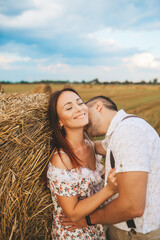 A couple in love is on a haystack at the sunset. Guy and girl love each other.