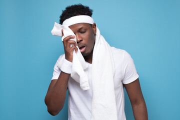 African young sportman wipes sweat off his face with a towel after exercise