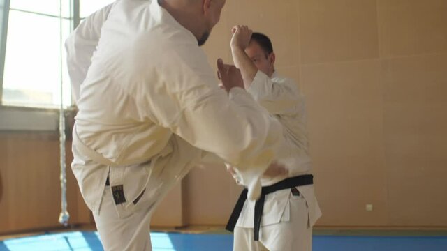 Senior man in kimono falling down after getting kick from newbie but gets up