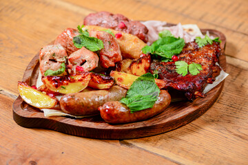 Georgian dinner. Meat, sausages and baked potatoes with fresh greenery served on a wooden board.