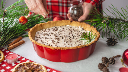 Homemade tart decorated with cocoa on a white table with pine branches. Table decoration for Christmas and new year