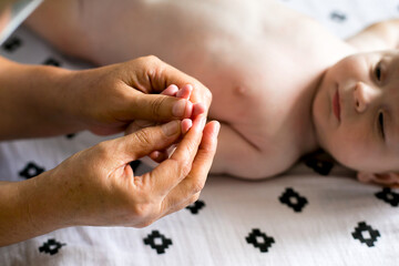 Obraz na płótnie Canvas Mother makes newborn baby massage, apply oil on the hand, with white background