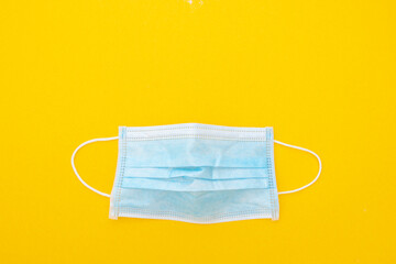 Surgical face mask to cover the mouth and nose. Protection concept. Yellow background, top view.