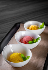 various ice cream desserts with mint leaf on black wooden table
