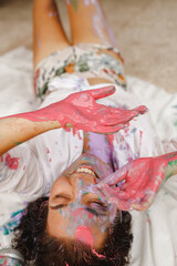 Young cheerful soiled in paint girl having fun, her hands in pink colors