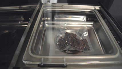 Close up of automated vacuum seal machine packing coffee beans in plastic bag
