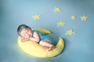 Cute newborn baby sleeping on a moon pillow
