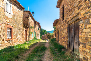 Fototapeta premium Santa Colomba de Somoza, Castilla y Leon / Spain - August 10, 2020: Rural scenery with unpaved street with old stone houses