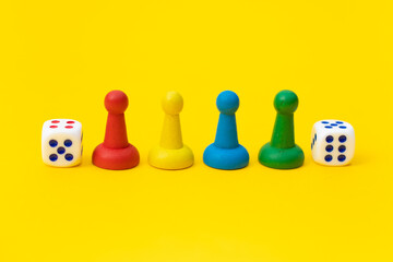 Colorful game chips and two dice are laid out on a yellow background: entertainment, games at home for the whole family, the concept of Board games. Board game. Table games