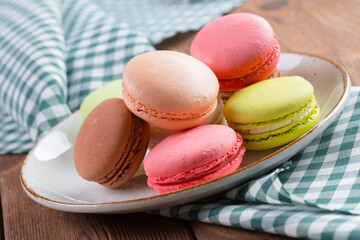 Colorful macaroon cookies on white plate close up