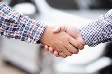 Congratulations. close up of young businessman shake hands investor between two colleagues. a successful deal. background car.