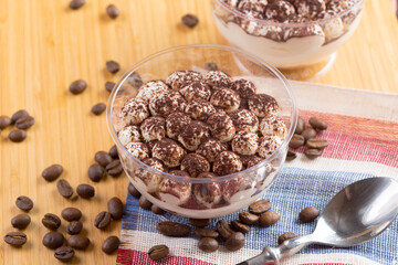 Tiramisu dessert in a glass cup on wooden table