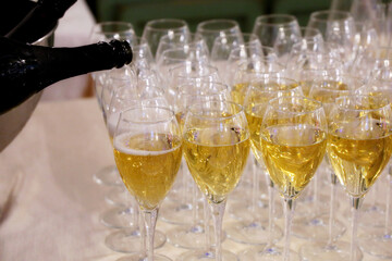 Sparkling wine pours from the bottle into the glasses in a restaurant. Concept of celebration, official reception, romantic party