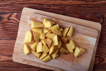 Serving of slices raw potatoes on wooden cutting boards and wooden rustic table. Top view.