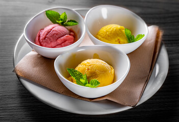 various ice cream desserts with mint leaf on black wooden table