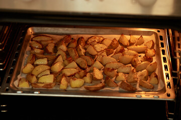 Delicious baked potatoes on baking sheet in oven. From top an angle.