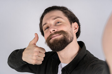 Young man hold the camera with hand and shows thumb up. Make selfie