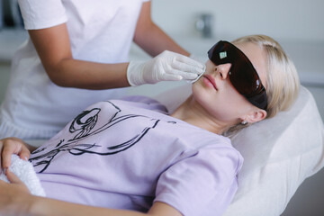 Hands of female beautician cleanses the skin. Facial skincare. Beautiful young woman on a cosmetology procedure