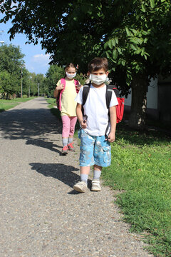 
a boy and a girl go to school with masks on their faces. Social distance in the school yard. Social distance on the way to school