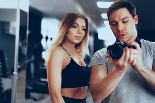 Photographer man taking a picture of a fit young girl in a gym