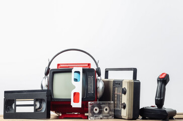 Retro portable mini tv set with headphones, 3d glasses, radio receiver, joystick, audio and video cassette on white background. Attributes 80s, retro style