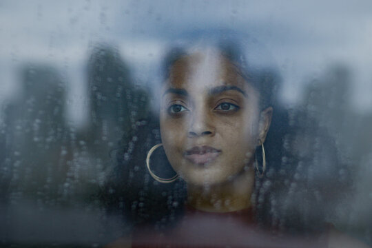 Portrait of young adult African American looking of of window during lockdown