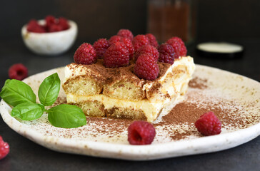 Tiramisu with raspberries on a dark concrete background. The classic Italian dessert is tiramisu.