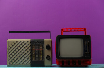 Retro media. Old portable tv, radio receiver on a purple background