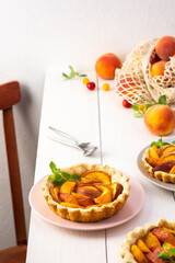 Open pie from shortcrust pastry with peaches, peach clafoutis on white table
