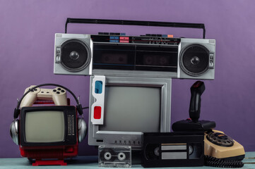 Fototapeta na wymiar Retro portable mini tv set, radio receiver, record player, headphones, joystick, 3d glasses, gamepad, audio and video cassette, phone on purple background. Attributes 80s, retro media, entertainment