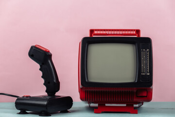 Retrogaming. Video game competition. Old TV with joystick on pink background. Attributes 80s