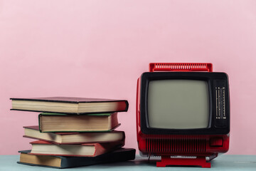 Retro tv and stack of books on pink background. TV distance learning.