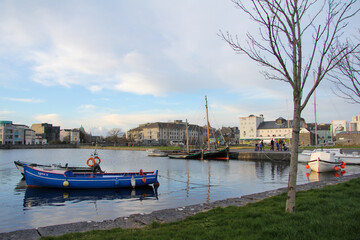 Fototapeta na wymiar Boats on the water with houses in the background in Galway, Ireland