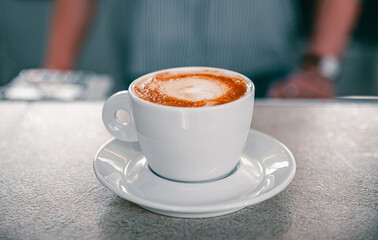 Cup of hot cappuccino coffee on bar counter in cafe