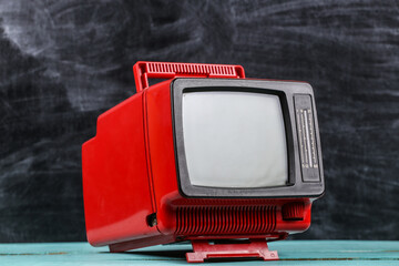 Red retro old school portable mini tv set on blackboard background