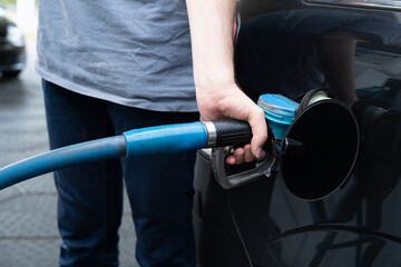 Male hand fills gasoline in a car with gas pump nozzle