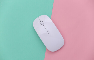 White modern wireless pc mouse on a blue-pink pastel background. Top view