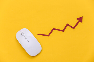 White mouse with a rising arrow on a yellow background. Online business, trading. Top view. Flat lay