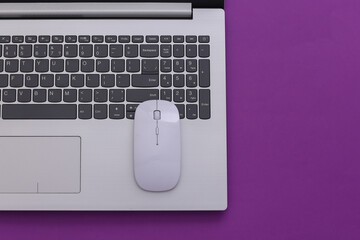 Laptop with pc mouse on purple paper background. Online workspace. Remote work. Studio shot. Top view. Flat lay