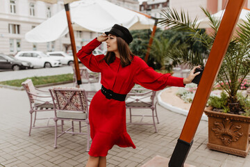 Dreamy 24 year old girl looks to distance with hope. Photo in European city of stylish model in...