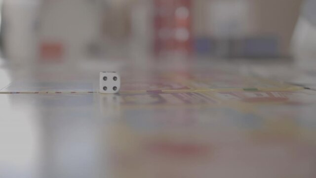 A hand throw a dice on a board game in slow motion