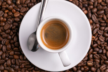 Mugful of coffee in white cup and saucer with coffee grains background