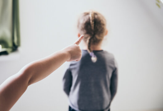 Child bully pointing finger at blurred unrecognizable victim and talking behind back. Bullying concept.