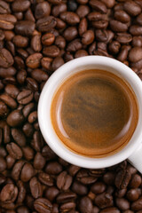 Mugful of coffee in white cup and saucer with coffee grains background
