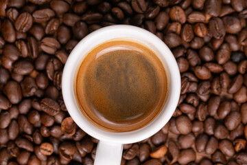 Mugful of coffee in white cup and saucer with coffee grains background
