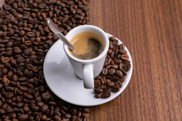 Mugful of coffee in white cup and saucer with coffee grains background