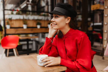 outside portrait in profile of model with lush eyelashes. Pretty girl drinks cappuccino and smiles...