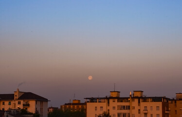 Fototapeta na wymiar Panoramic city moonset on a beautiful clear gradient coloured sky after sunrise on a summer morning
